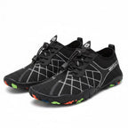 A pair of black water shoes with white geometric line patterns on the sides, black laces, and colourful soles.