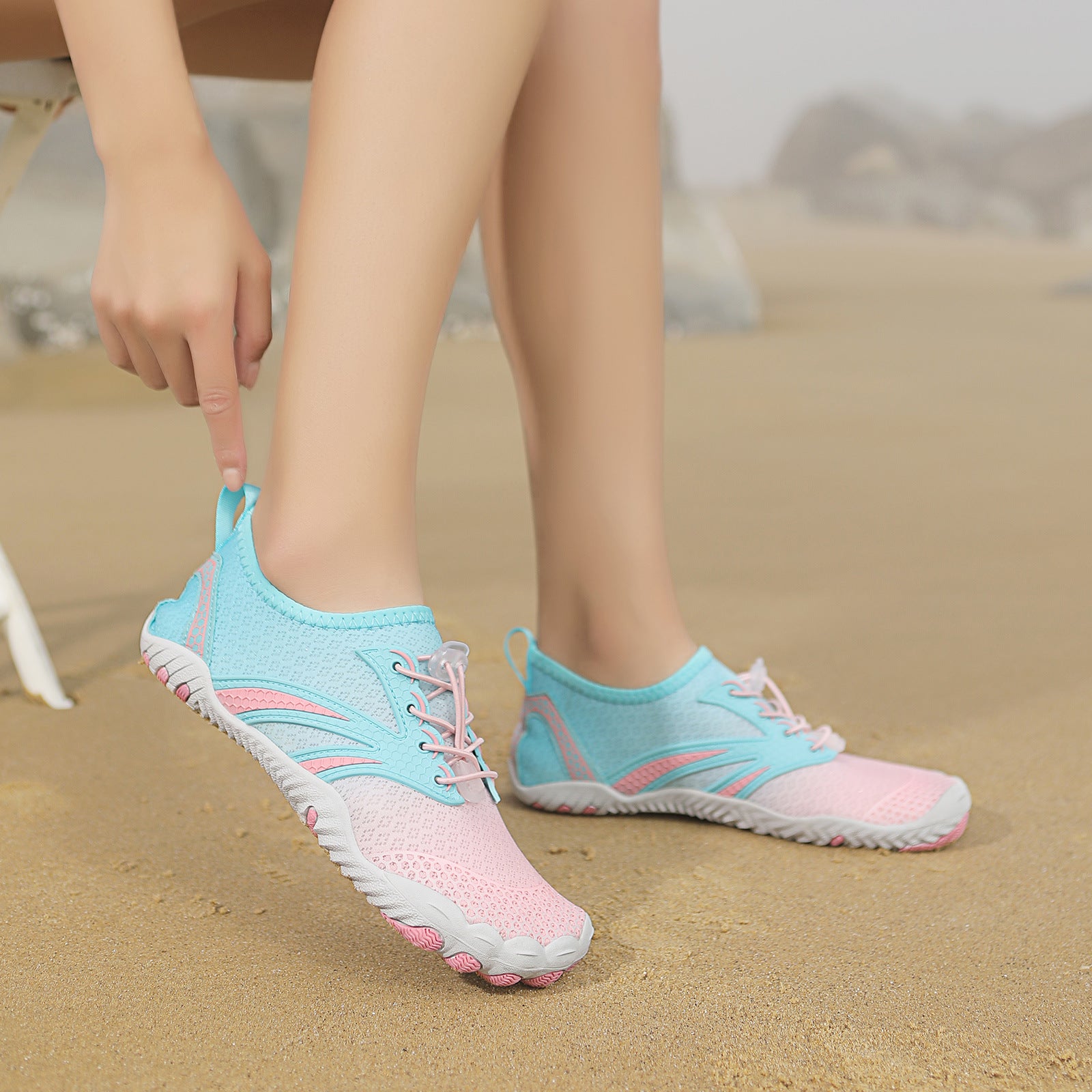 Light blue and pink water shoes on a sandy background
