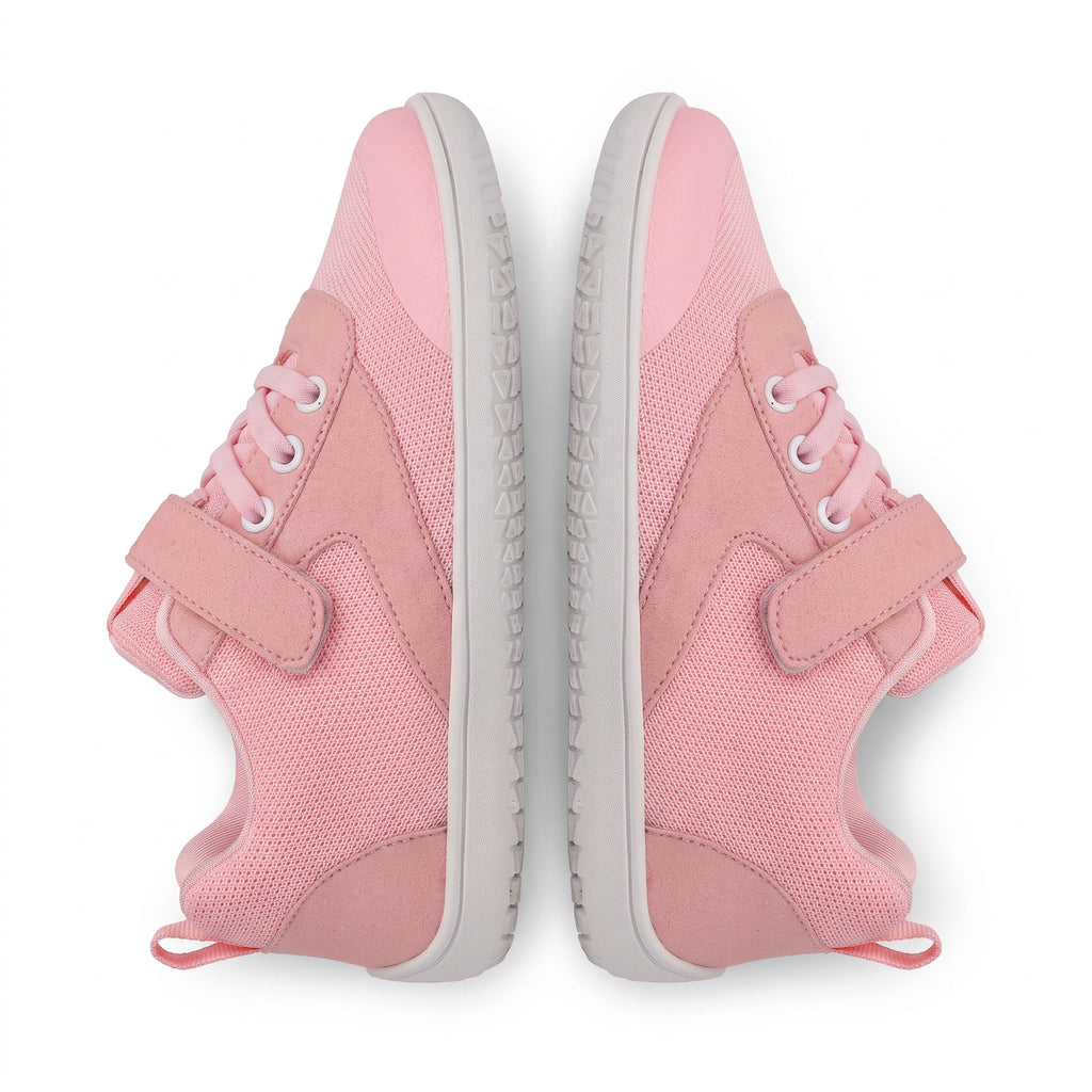 A pair of pink children's barefoot shoes shown from a top down view on a white background. The sneakers feature a mesh and suede like upper, pink laces, hook and loop strap closures, and light grey soles.