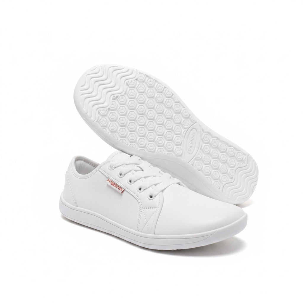 A pair of white low top Barefoot Shoes with one shoe shown from the side and the other displaying its textured white outsole.