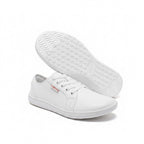 A pair of white low top Barefoot Shoes with one shoe shown from the side and the other displaying its textured white outsole.