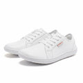 A pair of white low top casual sneakers with white laces.