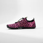 A single water shoe in a vibrant pink and black geometric pattern, shown in a side profile on a light grey studio background.