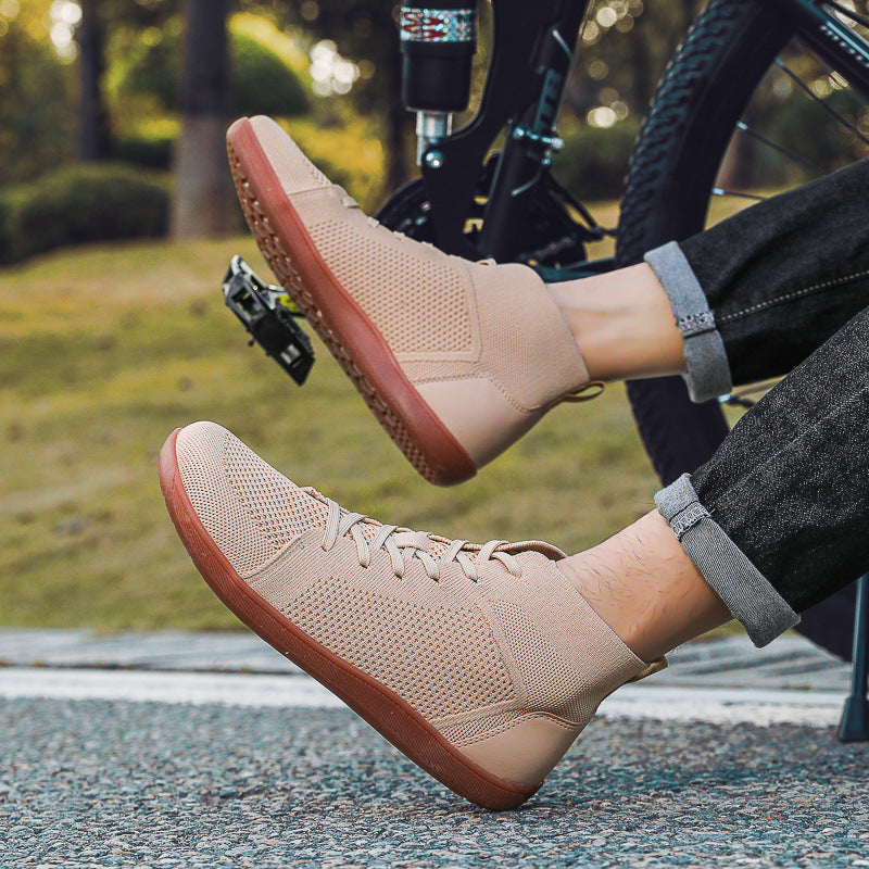 Beige sneakers with brown soles worn by a person sitting on a bench outdoors.