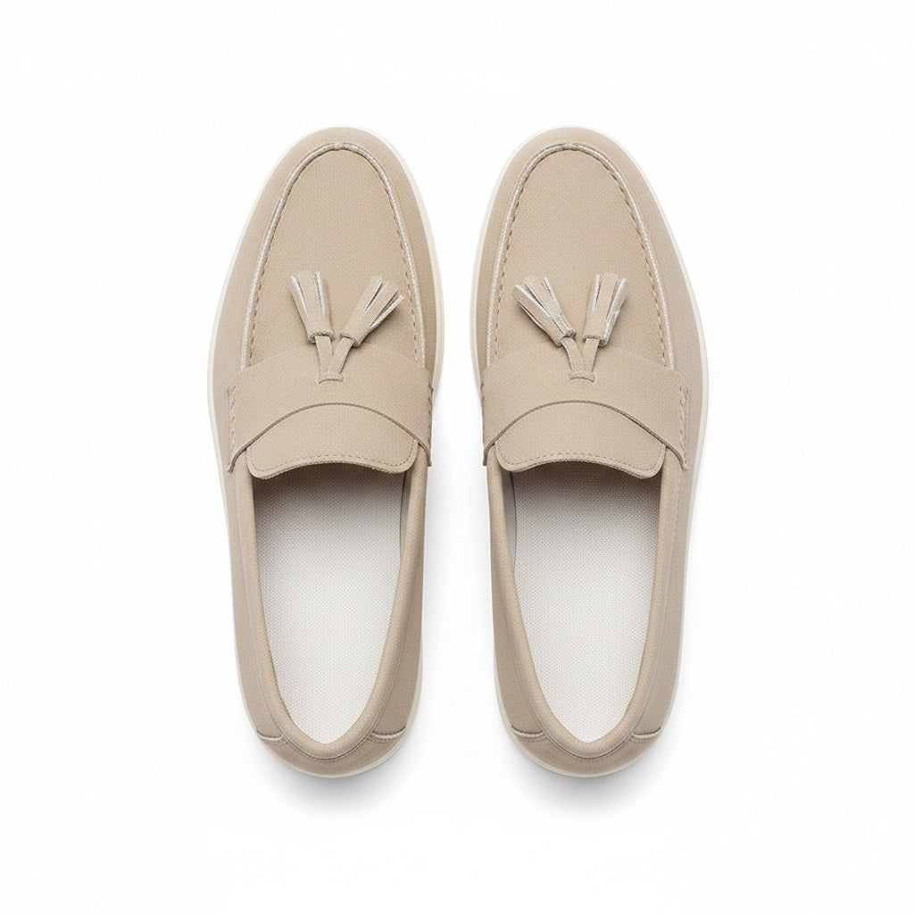 A pair of light beige leather tassel loafers shown from a top down view. 