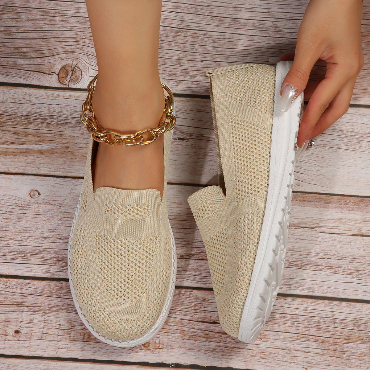 Beige slip on shoes with white soles on a wooden floor.