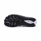 Bottom view of a black barefoot water shoe showing its flexible textured rubber sole