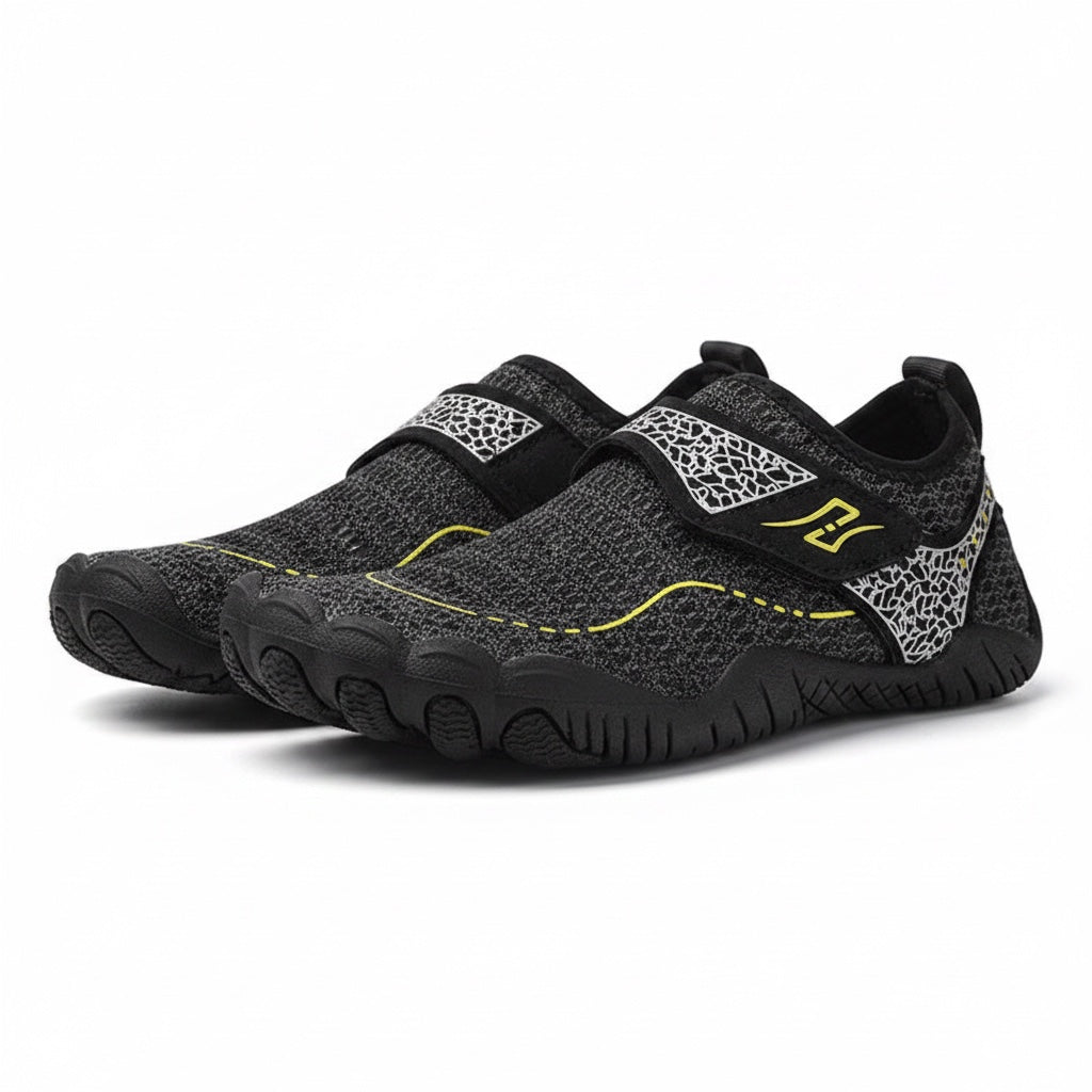 A pair of children's black water shoes with a textured knit upper, hook and loop strap closures, and yellow accents