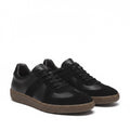 A pair of black leather and suede low top sneakers with black laces and brown gum soles