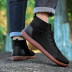 Black sneakers with brown soles worn outdoors