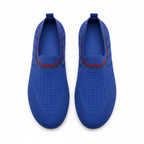 A pair of slip on water shoes in royal blue, featuring a textured grid pattern on the upper, a red and green stripe detail around the collar, and a pull tab at the heel.