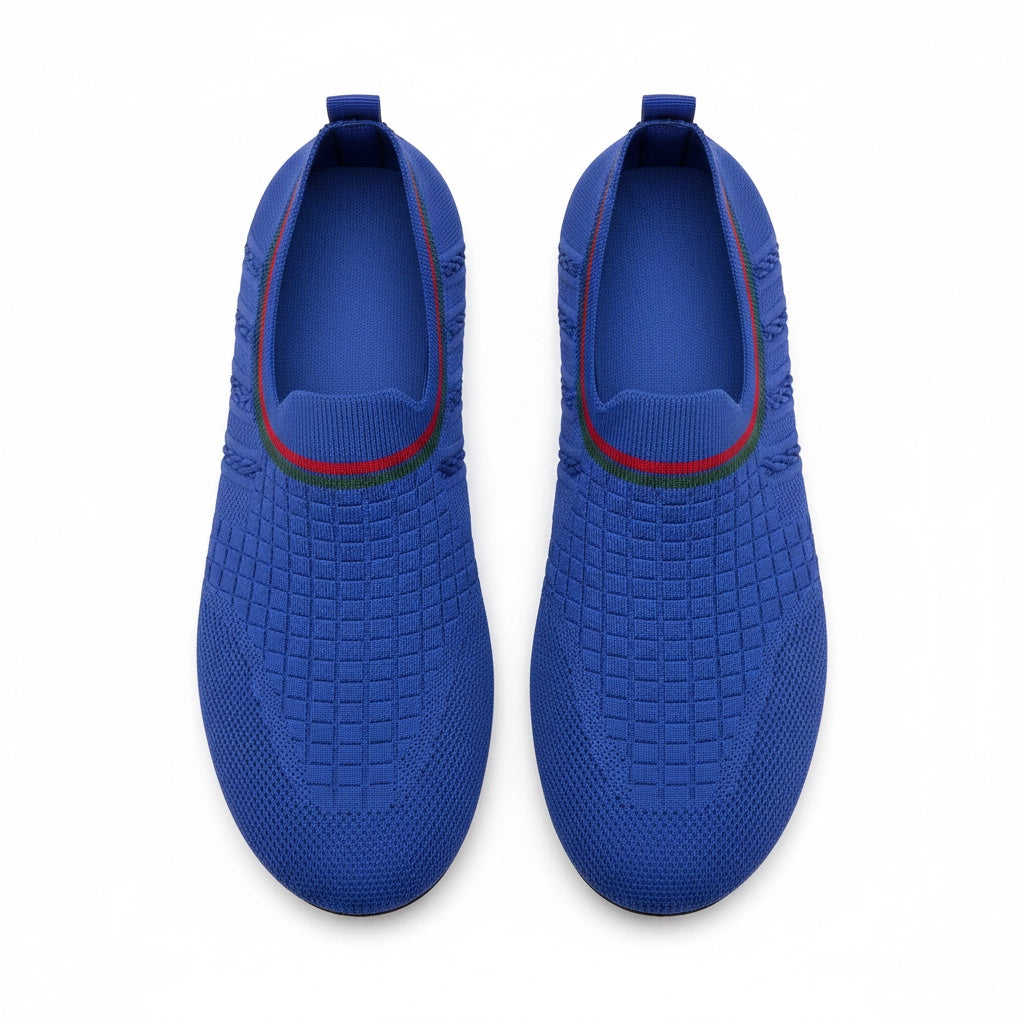 A pair of slip on water shoes in royal blue, featuring a textured grid pattern on the upper, a red and green stripe detail around the collar, and a pull tab at the heel.