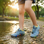 Child wearing grey kids water shoes while walking through shallow water outdoors
