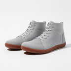 A pair of light grey high top sneakers with a perforated mesh upper, matching grey laces, and brown gum soles.