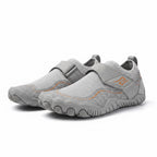 A pair of light grey children's slip on water shoes with hook and loop straps and subtle orange accents.