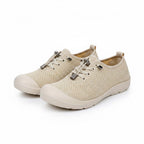 A pair of beige knit slip on sneakers with silver metal toggle laces and white soles