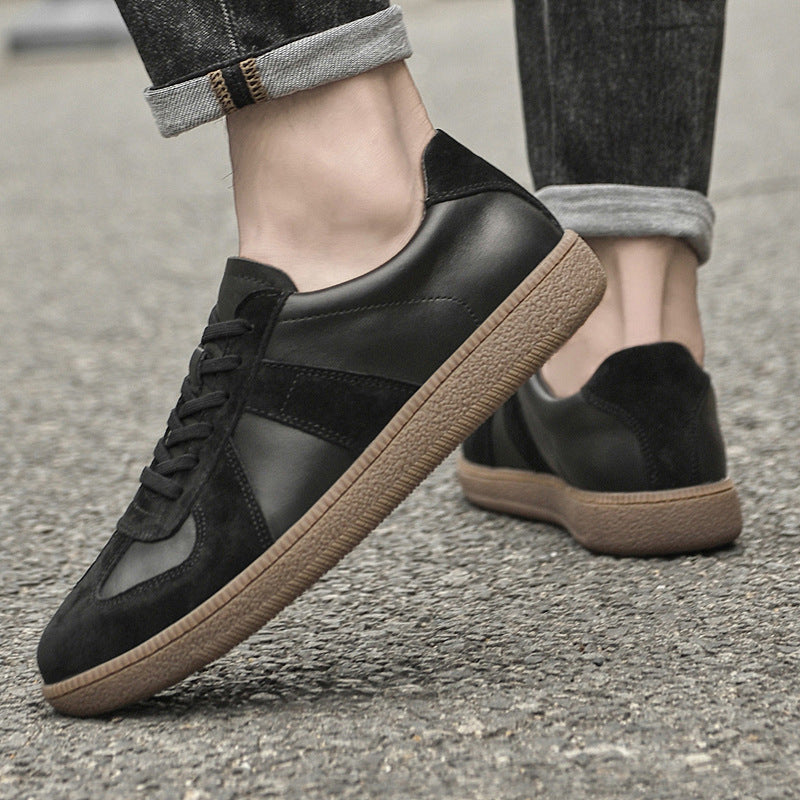 Black Loafers with brown soles worn by a model on a concrete surface