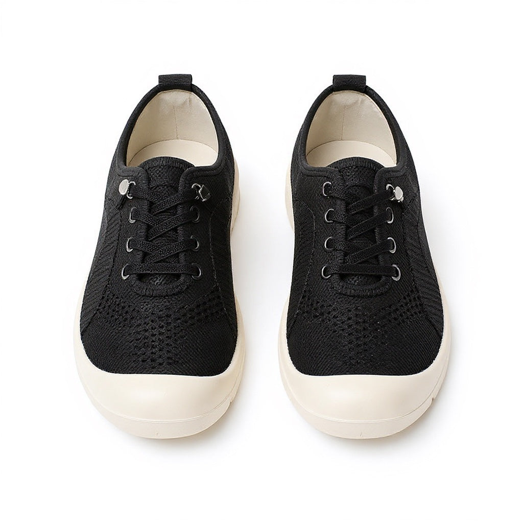 A pair of black low top lace up loafers shoes with a textured knit upper and thick white rubber soles.