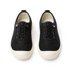 A pair of black low top lace up loafers shoes with a textured knit upper and thick white rubber soles.