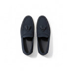 A pair of navy blue slip on loafers with tassel details.