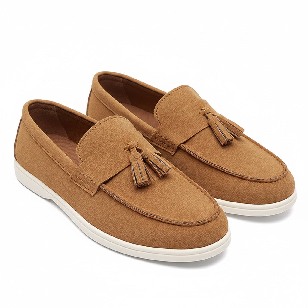 A pair of tan slip on loafers with matching leather tassels and white soles.