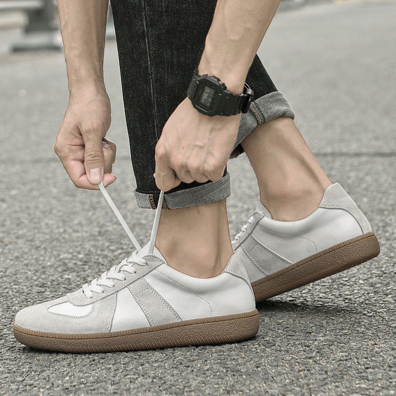 Person tying the laces of white  Loafers with brown soles on a street.
