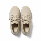 A pair of low-top canvas sneakers in a light beige colour, shown from a top-down view.