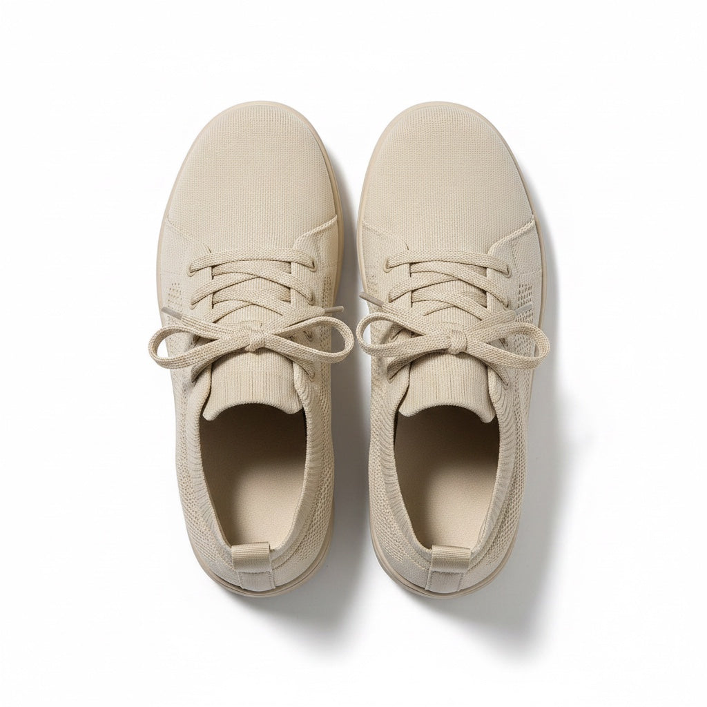 A pair of low-top canvas sneakers in a light beige colour, shown from a top-down view.