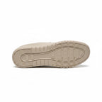 Bottom view of a beige men's knit barefoot shoe showing the patterned rubber outsole.