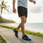 Black and blue Nomad barefoot shoes worn outdoors near the beach, showcasing their versatile design.