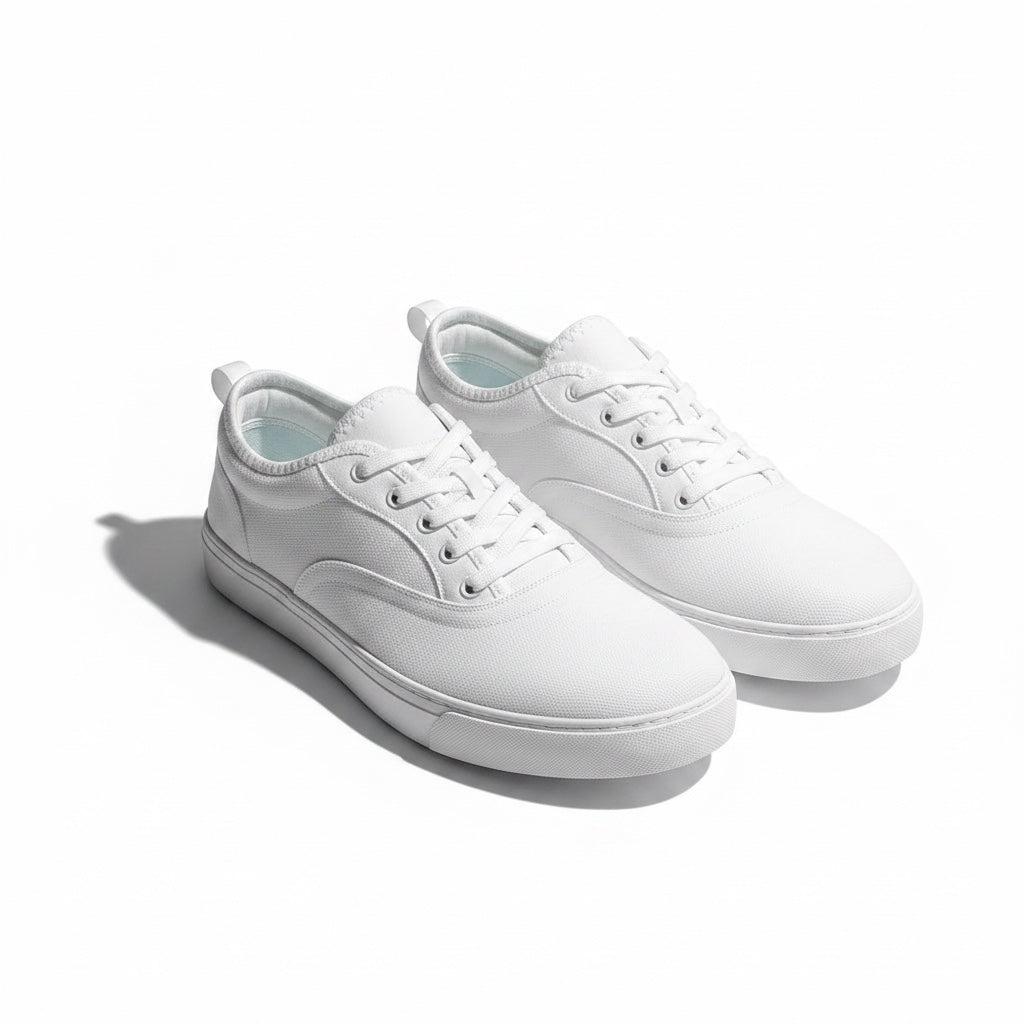 A pair of white low top canvas Barefoot Shoes  with white laces and white rubber soles.