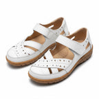 Pair of white women's comfort sandals with adjustable straps and flexible brown soles